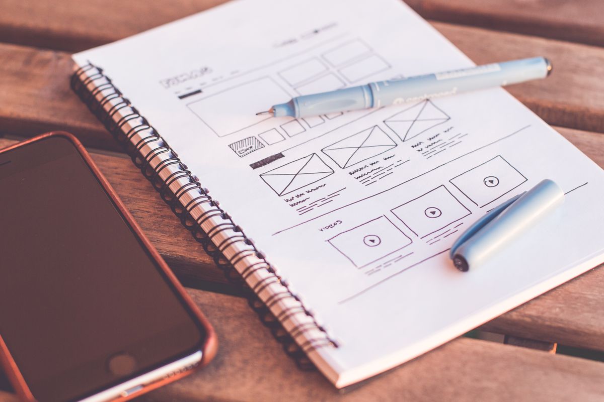 UX wireframe sketch on a notepad next to a phone